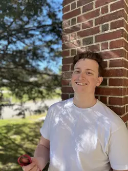 Alex Walley, tenor, standing in front of brick wall in Saratoga Springs, NY. Capital Region